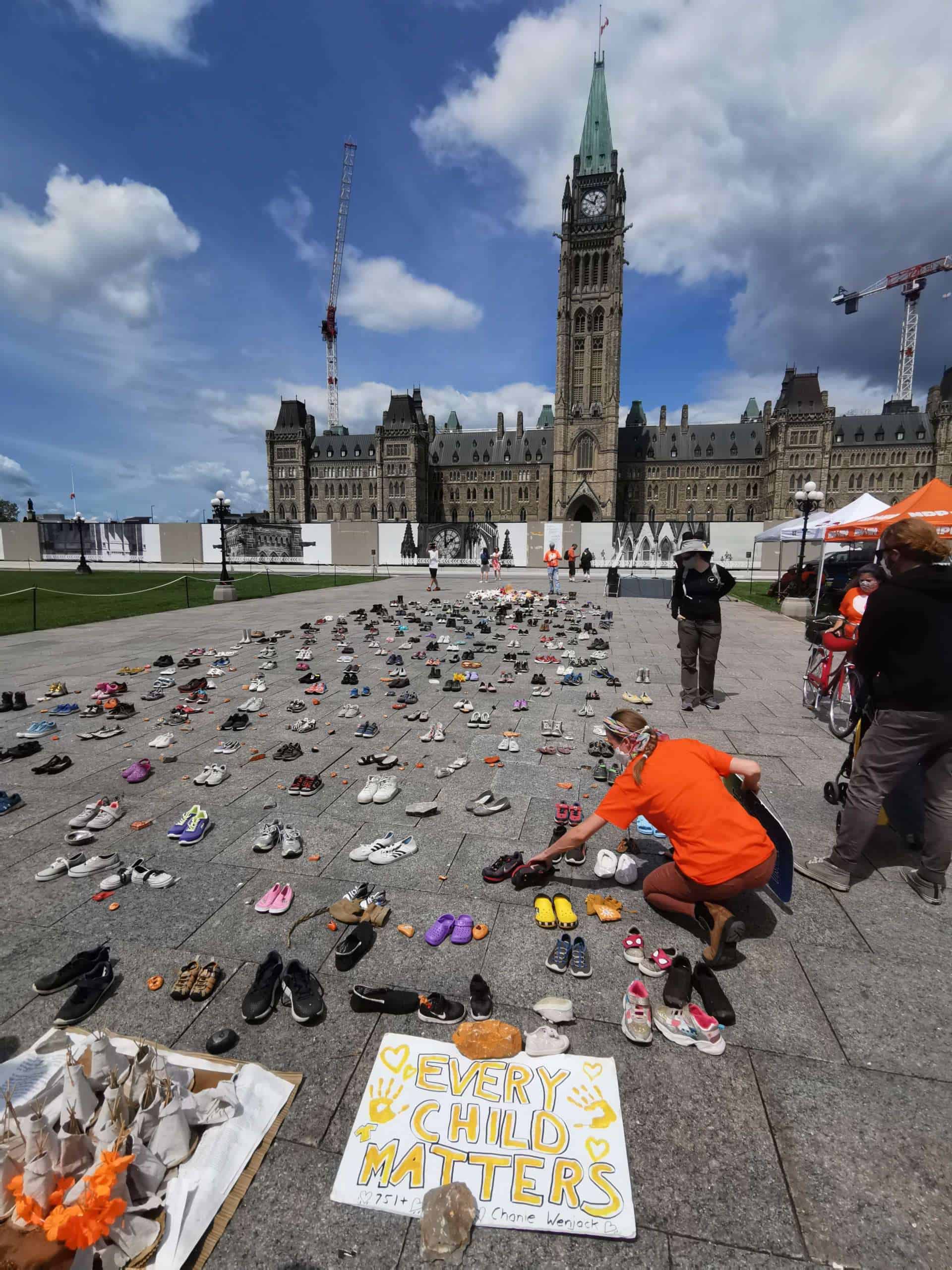 Mourner places a pairs of childrens' shoes—representing each child discovered in residential school gravesites across Canada in 2021—in front of Parliament Hill in Ottawa.
