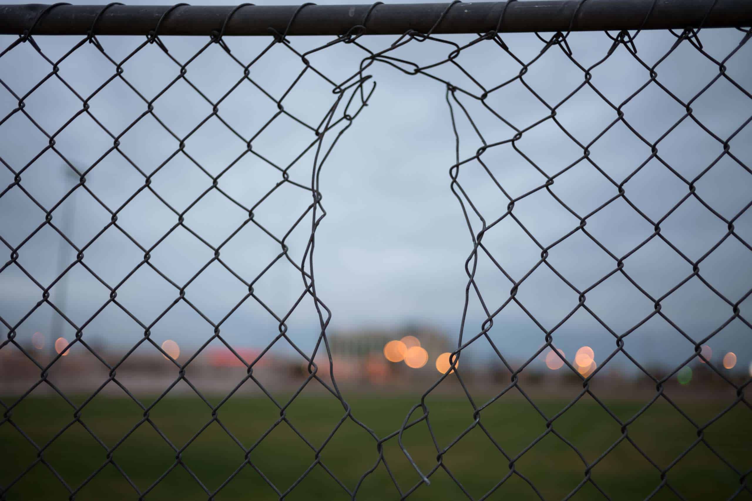 A chain link fence with a large gap in the middle.